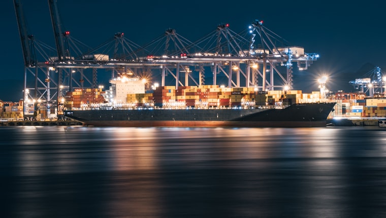 A container port at night, cranes loading a cargo ship