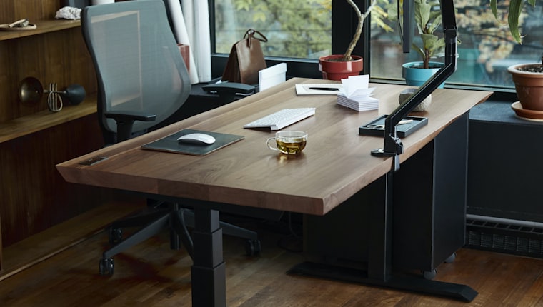 An empty office desk and chair beside a window