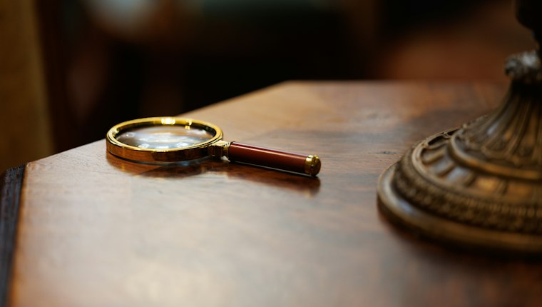 A brass magnifying glass on a wooden desk
