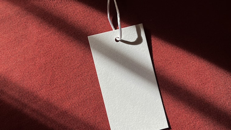 A blank white hang tag resting on red fabric